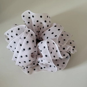 Close-up of elegant white chiffon hair scrunchie with classic black polka dot pattern