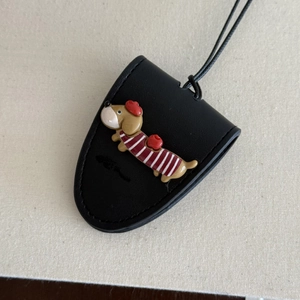 Detail showing a black leather sunglass holder with cute dachshund in striped shirt