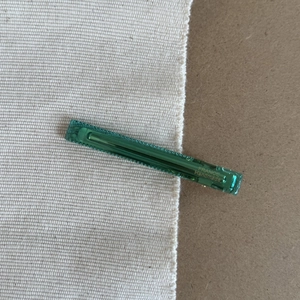 Close-up of translucent emerald green hair clip with gold France Handmade lettering