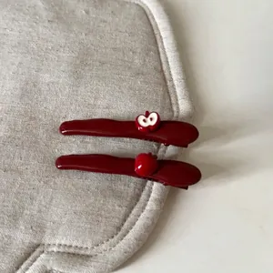 Deep red apple hair clips set featuring whole and sliced fruit on beige textured fabric