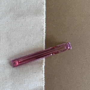 Detailed close-up of a pink translucent rectangular hair clip with a silver metal clasp