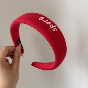 Detail of red padded sport headband with white embroidery and thick cotton texture