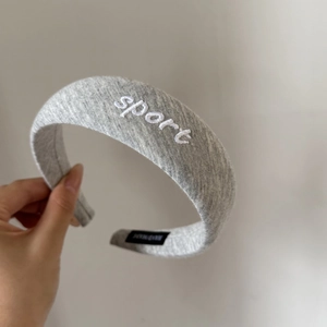 Detail view of grey knitted sports headband with white sport embroidery and soft texture