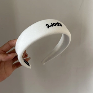 Detail of white cotton sponge headband with black sport embroidery and thick texture