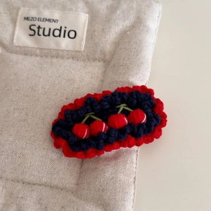 Détail d'une barrette cerise faite à la main au crochet avec des bords rouges ondulés