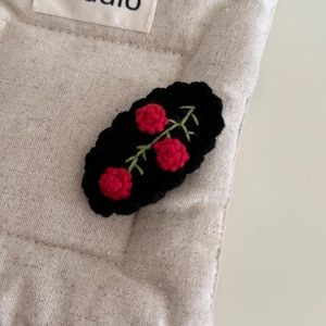 Détail macro d'une pince à cheveux crochetée avec roses rouges sur base noire tisée