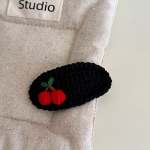 Détail de la pince à cheveux crochetée à la main avec cerises et base noire