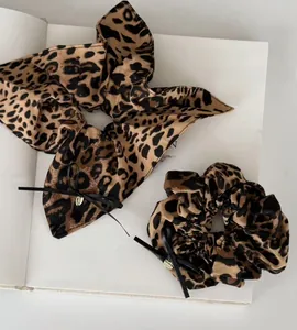 Détail d'un ensemble chouchou léopard avec nœud noir sur fond de livre blanc soigné