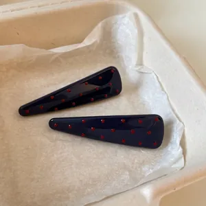 Paire de barrettes bleu marine à pois rouges avec finition lisse en résine sur papier
