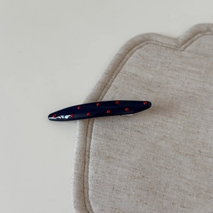 Barrette à paillettes bleu marine avec pois rouges sur fond de lin texturé