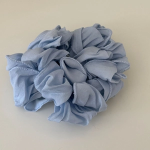 Dettaglio ravvicinato della trama del tessuto pieghettato e dei bordi arricciati dello scrunchie