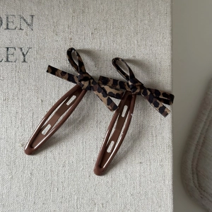 Vintage leopard print bowknot snap hair clips in brown set of two on fabric surface