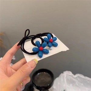 Detail showing two blue flower hair ties with high elasticity black bands for ponytail