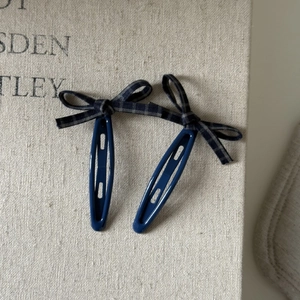 Detail of vintage navy blue plaid bow hair clips with oval hollow design and textured finish