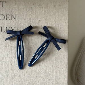 Detail of dark blue vintage plaid bow hair clips set on rustic beige linen background