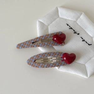 Dettaglio di fermagli per capelli a scacchi blu e marroni con cuori su base trapuntata