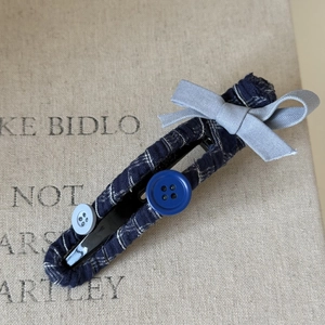 Blue plaid hair clip with satin bow and vintage buttons on beige textured background