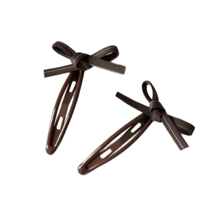 Pair of dark brown bow hair clips with white stitched edges and glossy BB clip base