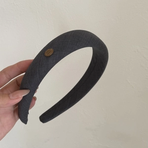 Détail d'un serre-tête large en tissu gris foncé avec rembourrage et badge bois