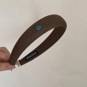 Vue détaillée du serre-tête rembourré marron foncé avec écusson Smile Happy élégant