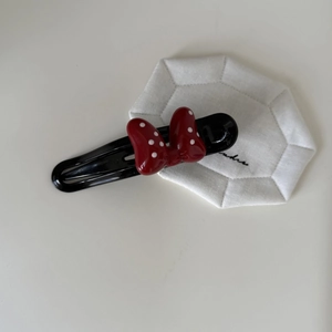 Detail of a vintage-style red and white polka dot bow hair clip with a sleek black base