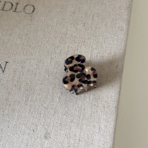Macro view of leopard print hair claw clip with acetate finish on textured fabric