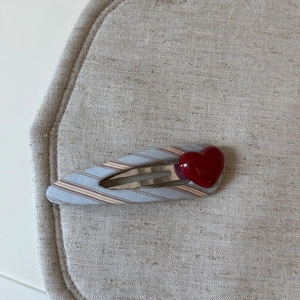 Dettaglio molletta per capelli a quadri blu con un cuore rosso 3D su fondo lino