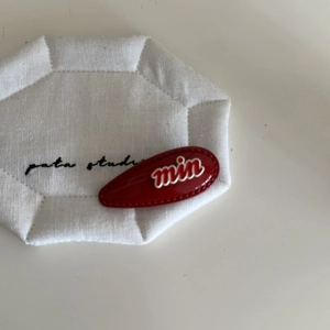 Detailed macro view of a red drop-shaped hair clip with white min text and dotted border