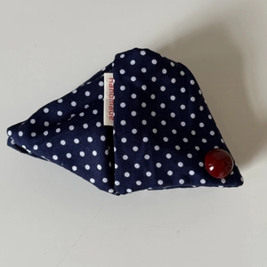 Détail d'une pochette triangle en tissu à pois bleu marine avec un bouton rouge