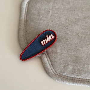 Detailed macro view of heart hair clip with denim texture and red enamel wavy border
