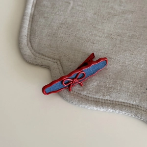 Detail of red wavy hair clip with blue denim fabric inlay and delicate bow decoration