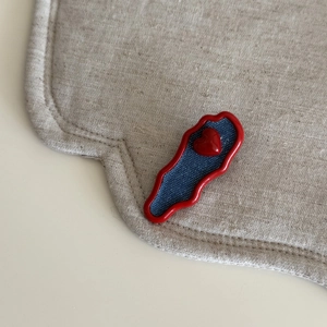 Close-up of red wavy frame hair clip with denim texture blue heart and central heart detail