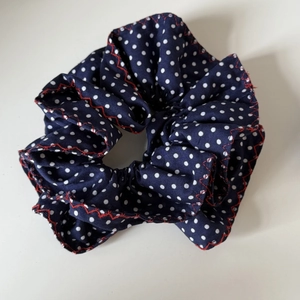 Détail d'un chouchou bleu marine à pois blancs avec une couture zigzag rouge vive