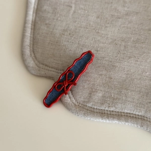Close-up of red wavy hair clip with blue denim fabric and a delicate red bow detail