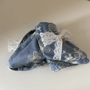 Detail einer blauen Denim-Haarspange mit weißer Blumenstickerei und zarter Spitzenschleife