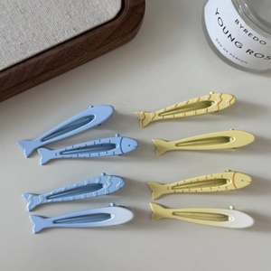 Dettaglio di otto fermagli per capelli a forma di pesce in blu e beige sulla scrivania