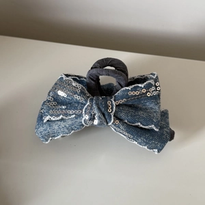 Detail einer blauen Denim-Haarklammer mit silbernen Pailletten und Spitzenbesatz