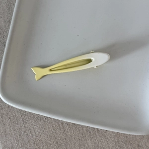 Dettaglio ravvicinato della clip per capelli a forma di pesce con finitura gialla