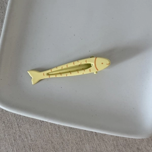 Dettaglio del fermaglio per capelli a forma di pesce giallo con strisce arancioni