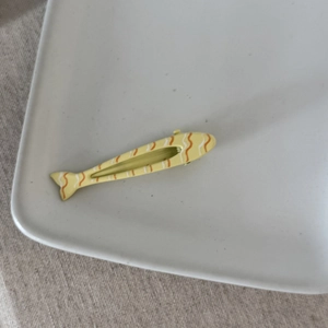 Graziosa clip per capelli a forma di pesce giallo con onde arancioni su piatto