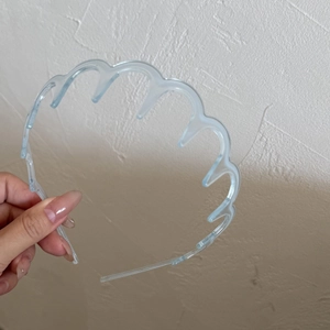 Gros plan du serre-tête ondulé bleu clair transparent avec dents antidérapantes pour cheveux