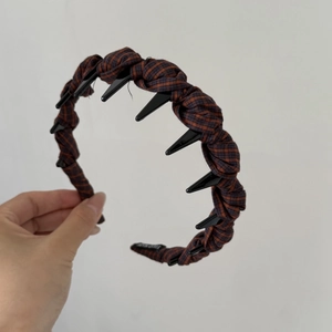 Close-up of a brown plaid fabric headband featuring a black plastic anti-slip inner tooth comb