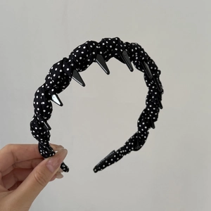 Detail showing inner tooth comb of the navy polka dot headband with Handmade label