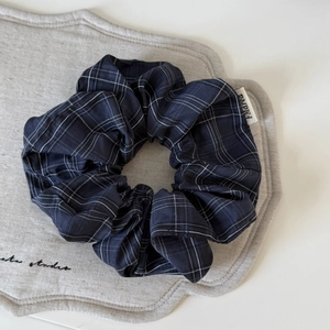 Detail of navy blue plaid scrunchie with classic grid pattern and woven fabric texture