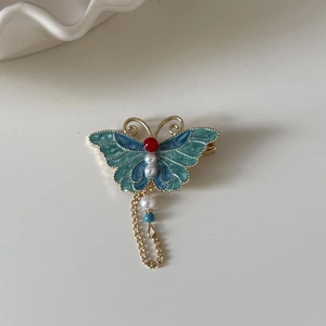 Detail einer blauen Emaille-Schmetterlings-Haarspange mit goldener Fransenkette