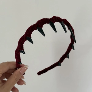 Detail view of burgundy velvet headband with black plastic shark teeth for secure grip