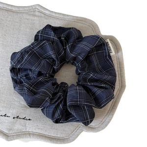 Classic navy blue plaid oversized scrunchie with a white fabric logo tag on grey mat