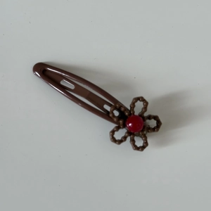 Close-up of brown dog hair clip featuring a resin flower with a red rhinestone center