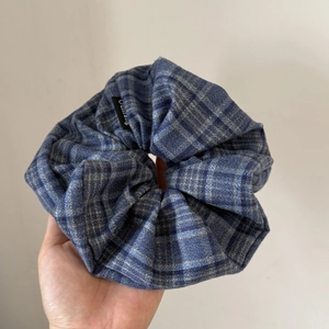 Detail showing blue plaid scrunchie fabric and sewn brand label for bun hair tie