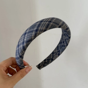 Detail of blue and grey plaid fabric texture on a winter hairband held in hand